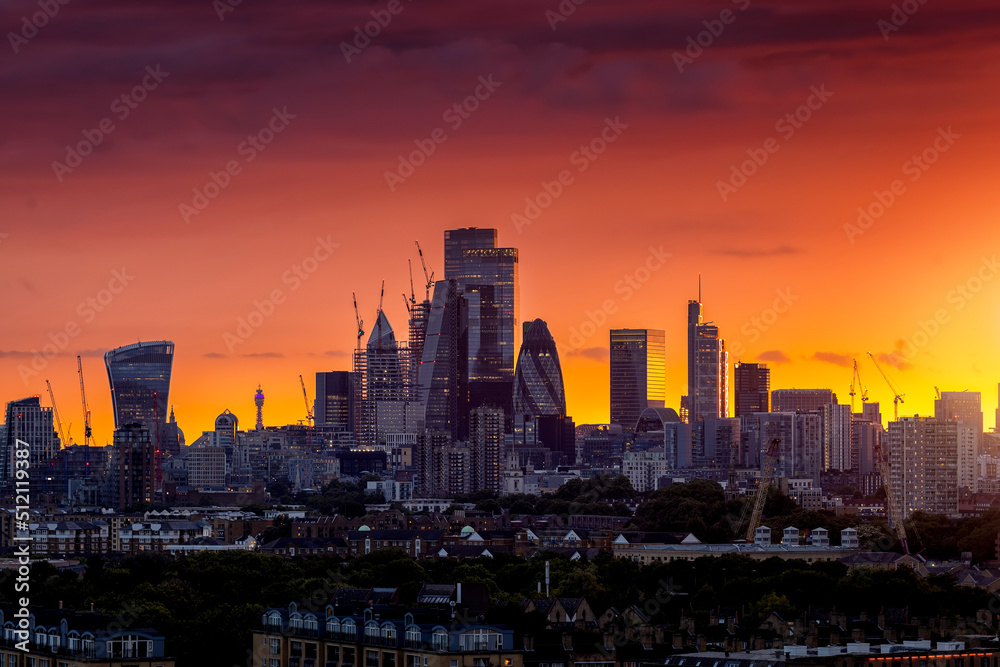 The modern skyline of the City of London during a fiery summer sunset with the skyscrapers reflecting the warm sunlight