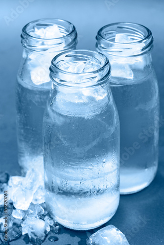 Glass bottles with cold water and ice