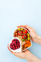 Hands holding heart shaped dish full of healthy diet food