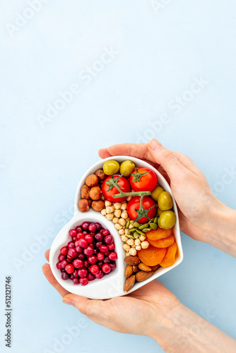 Hands holding heart shaped dish full of healthy diet food