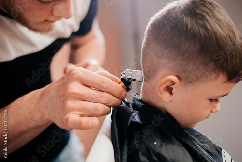 The hairdresser cuts the child's hair