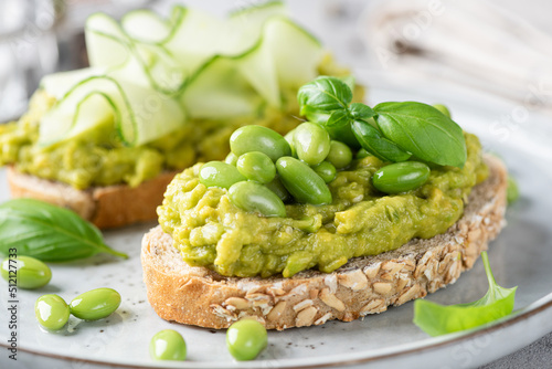 Fresh green avocado toasts with edamame beans and cucumber toppings. Clean eating, healthy vegan food concept. Closeup view