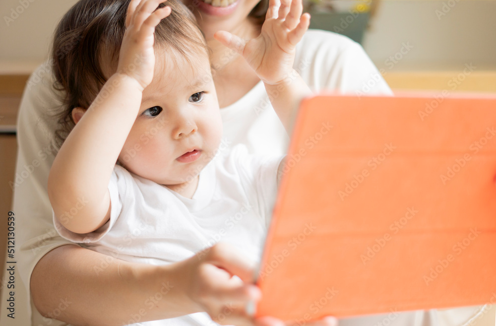 Naklejka premium 母親と一緒にタブレットPCを見ることを楽しんでいるハーフの男の子