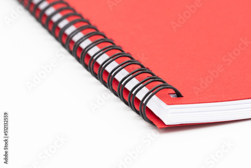 Close up of spirall notebook with red cover on white background photo