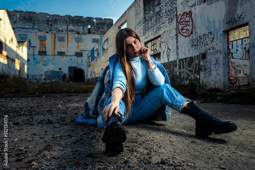 young model woman sitting on the ground of an abandoned factory for fashion photoshoot during sunset © Marcelo