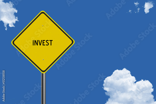 The word Invest on a yellow road sign on a blue sky background.  Inspirational concept for success in life.