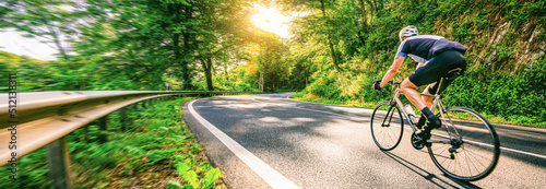 Obraz na płótnie Mature Adult on a racing bike climbing the hill at forest landscape france country road - motion blur w salonie