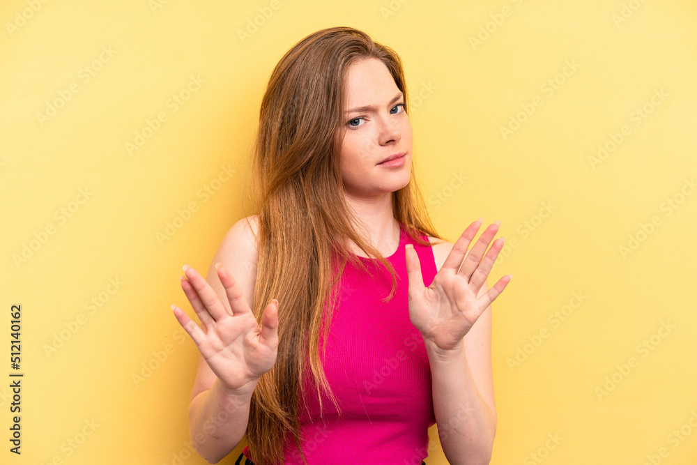 Young caucasian woman isolated on yellow background rejecting someone showing a gesture of disgust. Young caucasian woman isolated on yellow background rejecting someone showing a gesture of disgust.