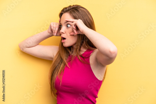 Young caucasian woman isolated on yellow background keeping eyes opened to find a success opportunity.