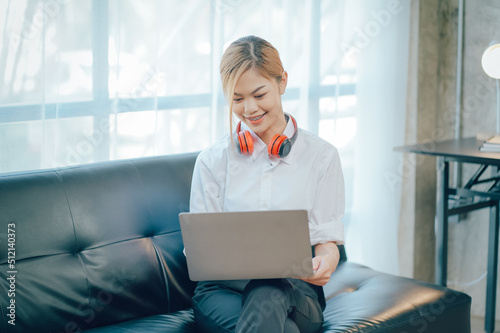 Young adult happy smiling Hispanic Asian student wearing headphones talking on online chat meeting using laptop in university campus or at virtual office. College female student learning remotely