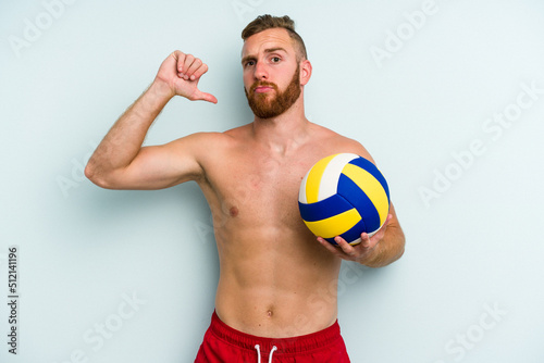 Young caucasian man playing volleyball isolated on blue background showing a dislike gesture, thumbs down. Disagreement concept.