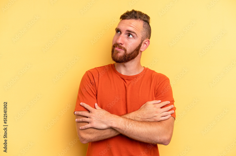 Young caucasian man isolated on yellow background dreaming of achieving goals and purposes