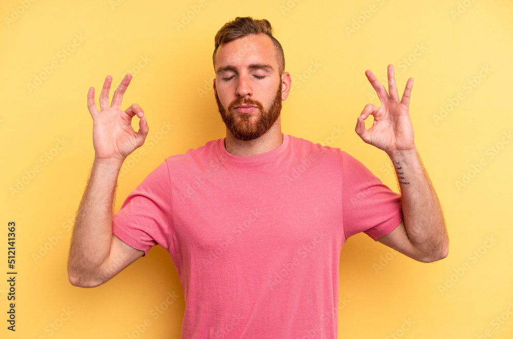 Young caucasian man isolated on yellow background relaxes after hard working day, she is performing yoga. Young caucasian man isolated on yellow background relaxes after hard working day, she is performing yoga.