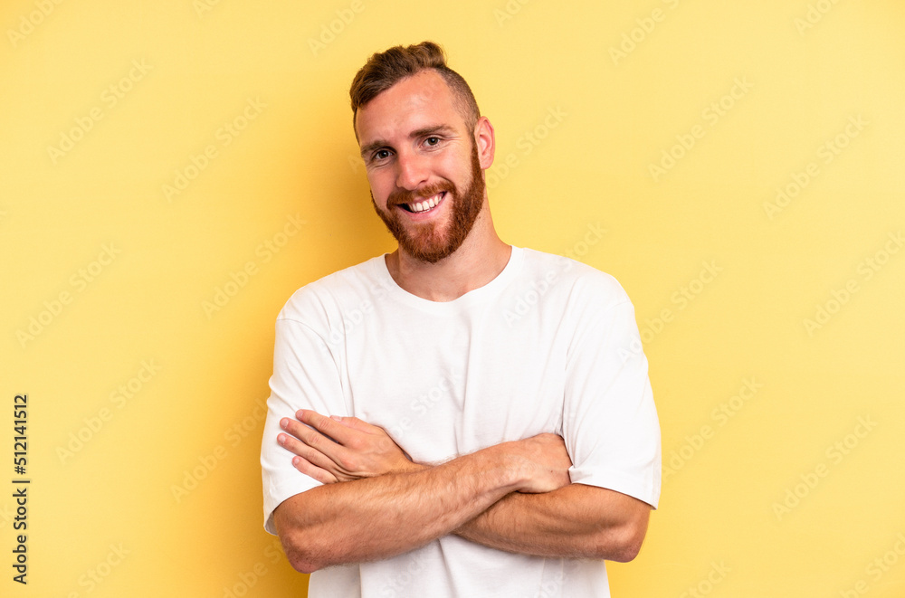 Young caucasian man isolated on yellow background who feels confident, crossing arms with determination. Young caucasian man isolated on yellow background who feels confident, crossing arms with determination.