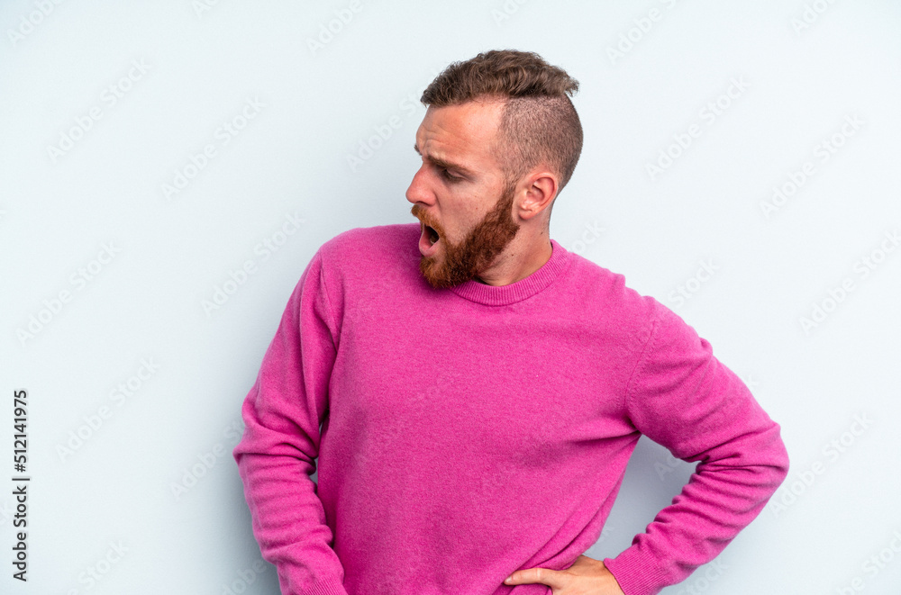 Young caucasian man isolated on blue background suffering a back pain. Young caucasian man isolated on blue background suffering a back pain.