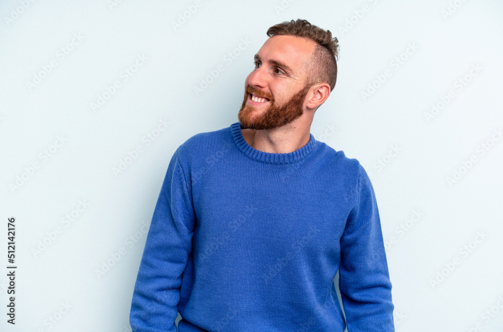 Young caucasian man isolated on blue background relaxed and happy laughing, neck stretched showing teeth. Young caucasian man isolated on blue background relaxed and happy laughing, neck stretched showing teeth.