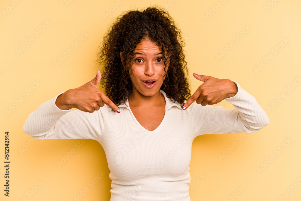 Young Brazilian woman isolated on yellow background points down with fingers, positive feeling. Young Brazilian woman isolated on yellow background points down with fingers, positive feeling.