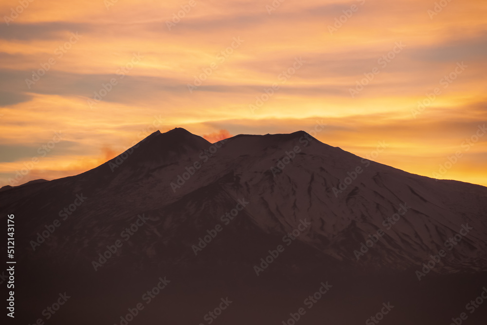 Panoramic view on silhouette of hills during twilight. Watching beautiful sunset behind volcano Mount Etna near Castelmola, Taormina, Sicily, Italy, Europe, EU. Clouds with vibrant red orange colors
