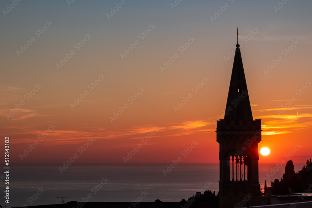 Watching beautiful sunrise at the Mediterranean sea in Taormina, Sicily, Italy, Europe, EU. Silhouette of tower of church Chiesa di Sant Antonio da Padova in the foreground. Vibrant red orange colors Watching beautiful sunrise at the Mediterranean sea in Taormina, Sicily, Italy, Europe, EU. Silhouette of tower of church Chiesa di Sant Antonio da Padova in the foreground. Vibrant red orange colors