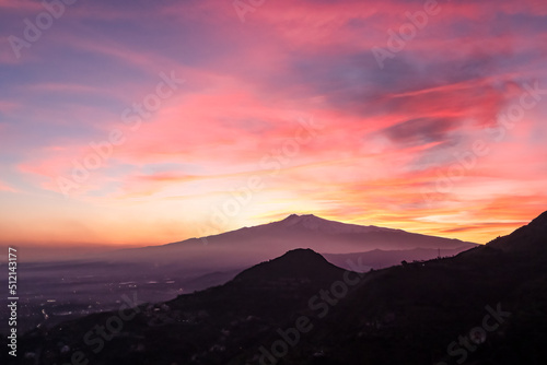 Panoramic view on silhouette of hills during twilight. Watching beautiful sunset behind volcano Mount Etna near Castelmola  Taormina  Sicily  Italy  Europe  EU. Clouds with vibrant red orange colors