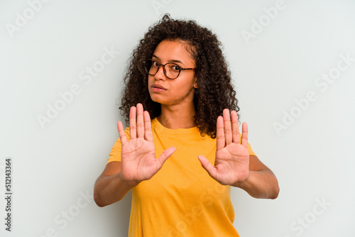 Young Brazilian woman isolated on blue background standing with outstretched hand showing stop sign, preventing you.