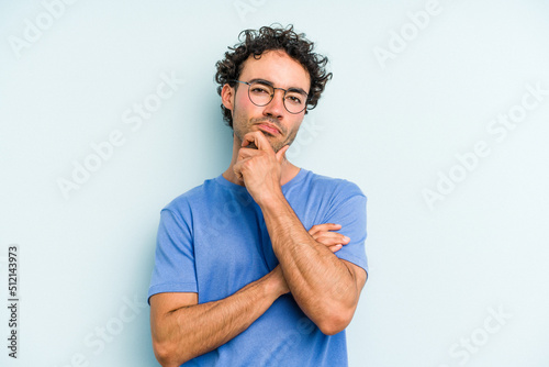 Fotografia Young caucasian man isolated on blue background thinking and looking up, being reflective, contemplating, having a fantasy