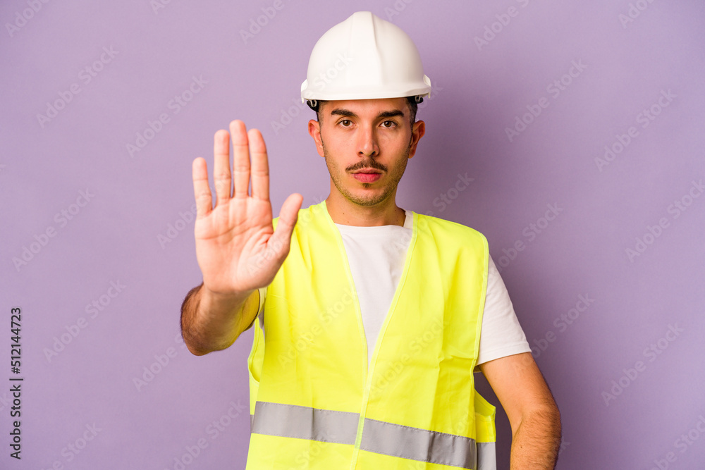 Young hispanic worker man isolated on purple background standing with outstretched hand showing stop sign, preventing you.