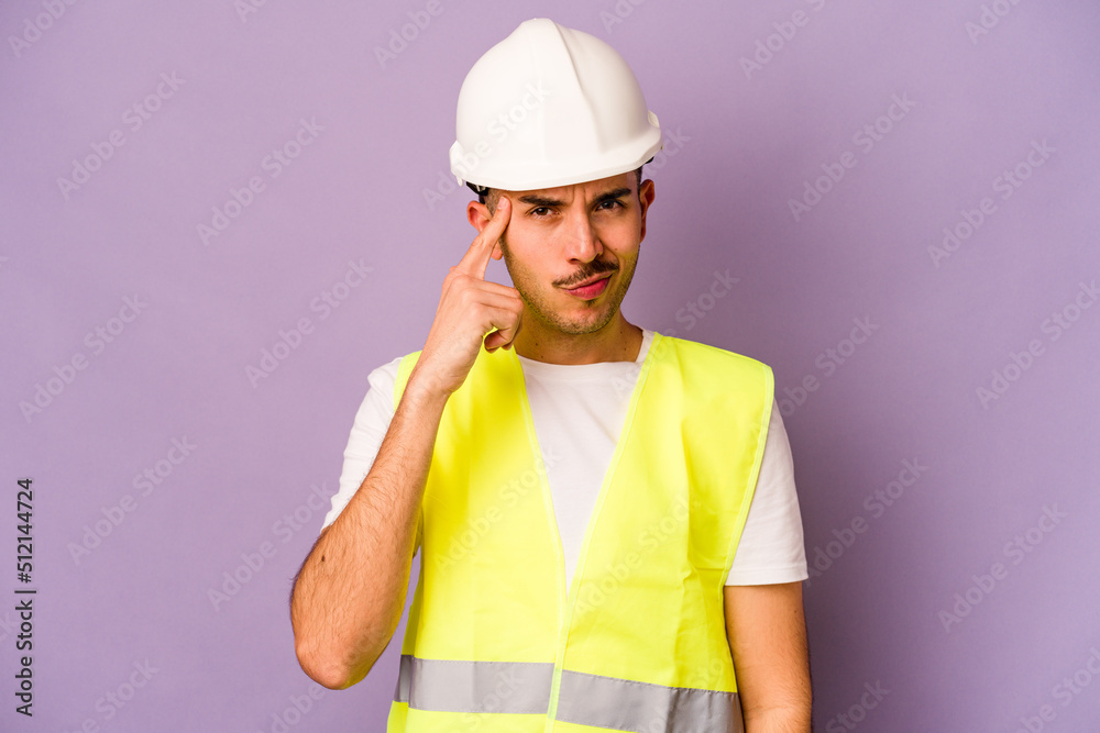 Young hispanic worker man isolated on purple background pointing temple with finger, thinking, focused on a task.