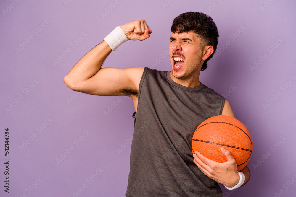 Young hispanic basketball player man isolated on purple background raising fist after a victory, winner concept.