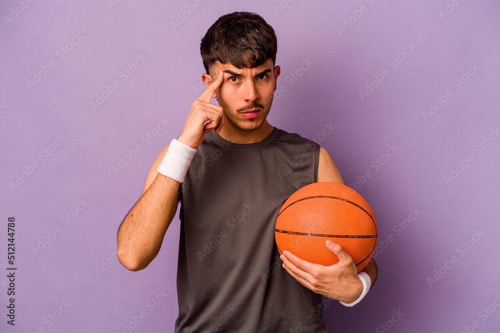 Young hispanic basketball player man isolated on purple background pointing temple with finger, thinking, focused on a task.