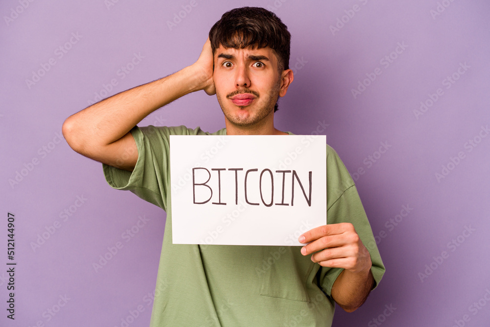 Young hispanic man holding bitcoin placard isolated on purple background being shocked, she has remembered important meeting.