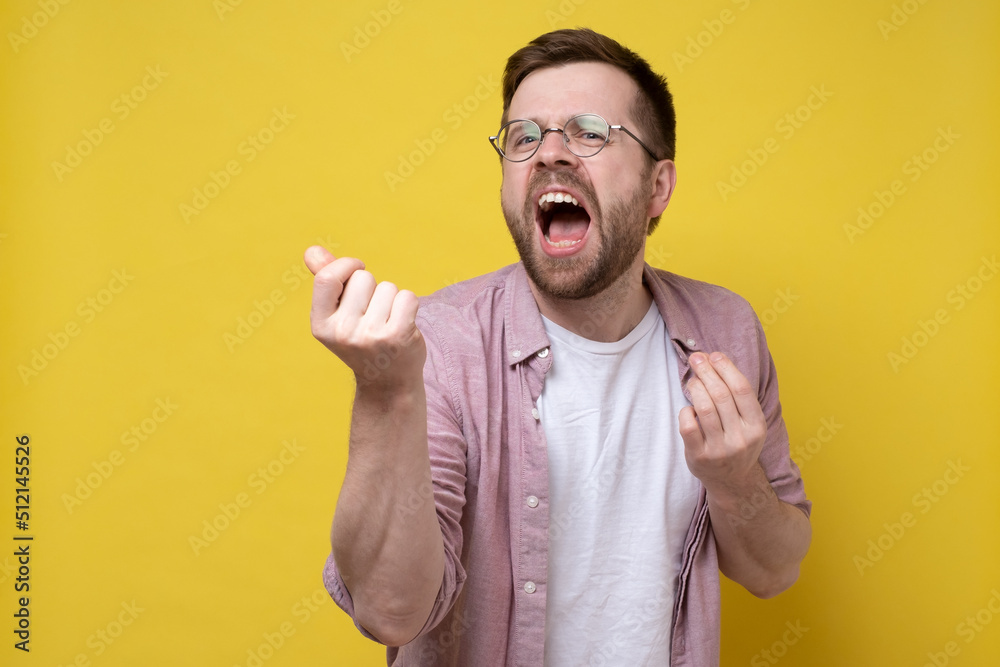 Creative man emotionally says something or dances or sings, gesticulating with his hands. Yellow background. Creative man emotionally says something or dances or sings, gesticulating with his hands. Yellow background.
