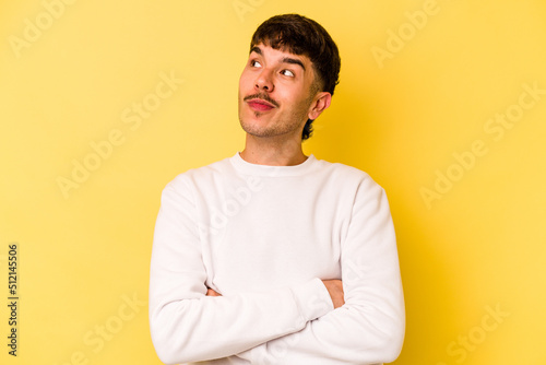 Young caucasian man isolated on yellow background dreaming of achieving goals and purposes