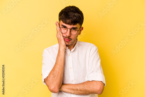 Young caucasian man isolated on yellow background who is bored, fatigued and need a relax day.