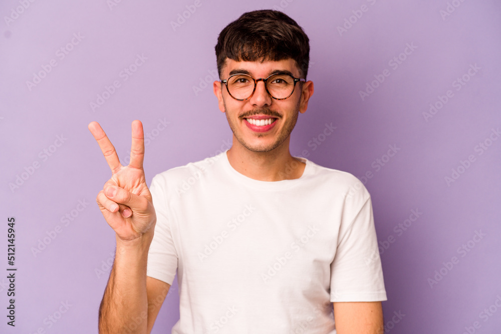 Young caucasian man isolated on purple background showing victory sign and smiling broadly. Young caucasian man isolated on purple background showing victory sign and smiling broadly.