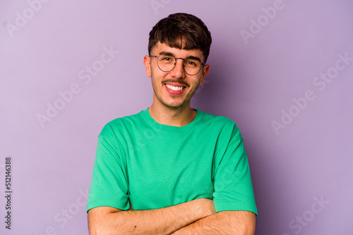 Young caucasian man isolated on purple background who feels confident, crossing arms with determination.