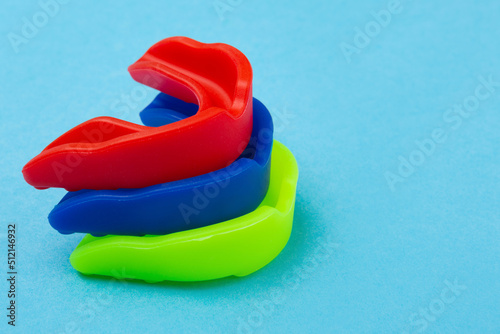 three boxing mouth guards in blue, red and green, lie one on top of the other photo