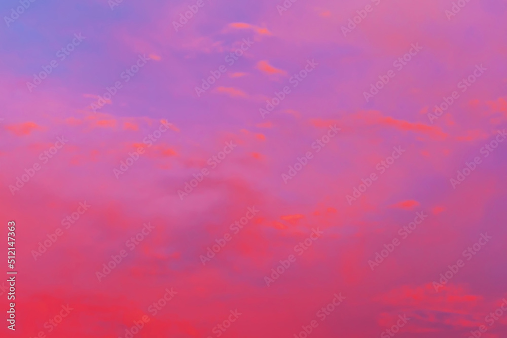 Clouds illuminated by the setting sun. Red sunset in the evening sky. Colorful dramatic view with red and purple clouds.