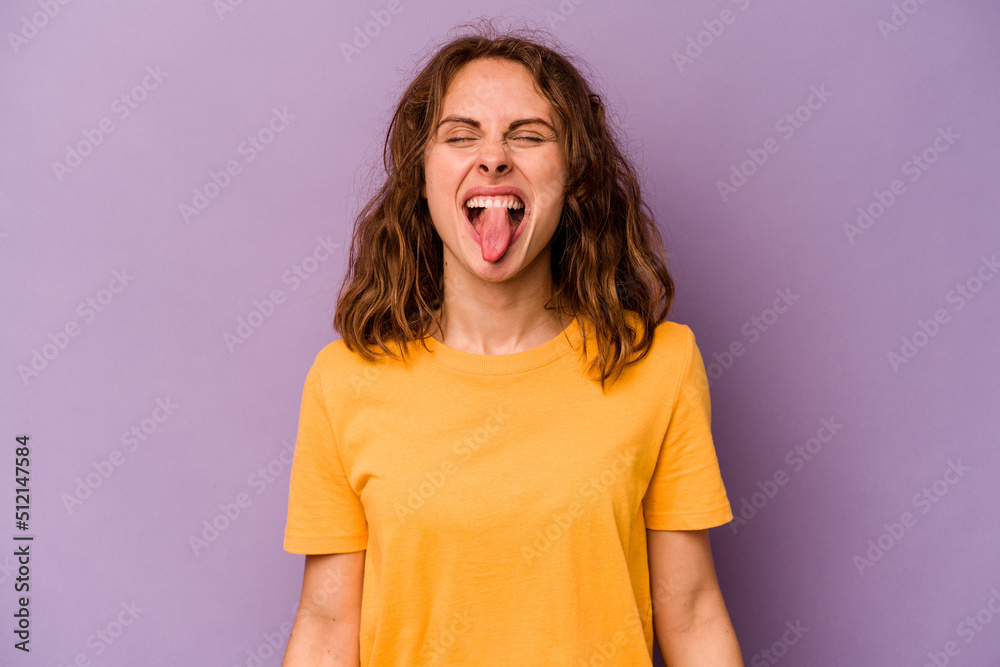Young caucasian woman isolated on purple background funny and friendly sticking out tongue. Young caucasian woman isolated on purple background funny and friendly sticking out tongue.