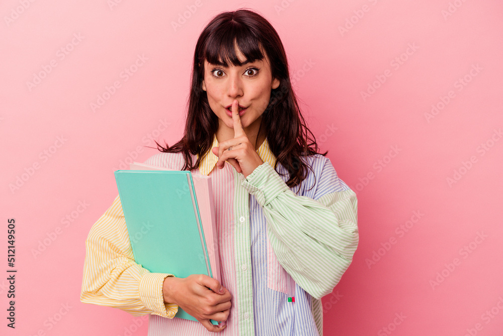 Young student caucasian woman holding books isolated on pink background keeping a secret or asking for silence. Young student caucasian woman holding books isolated on pink background keeping a secret or asking for silence.