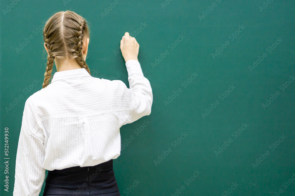 A photo of a smart student about to write something on the blackboard. Space for text. The concept of education, back to school. High quality photo