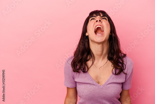 Foto Young caucasian woman isolated on pink background shouting very angry, rage concept, frustrated