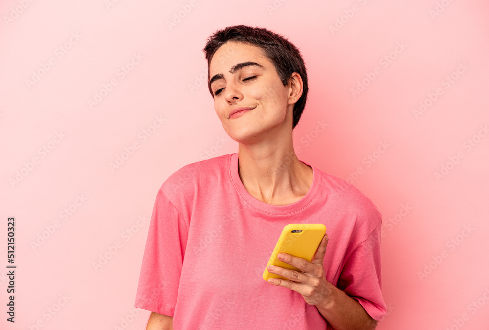 Young caucasian woman holding mobile phone isolated on pink background dreaming of achieving goals and purposes Young caucasian woman holding mobile phone isolated on pink background dreaming of achieving goals and purposes