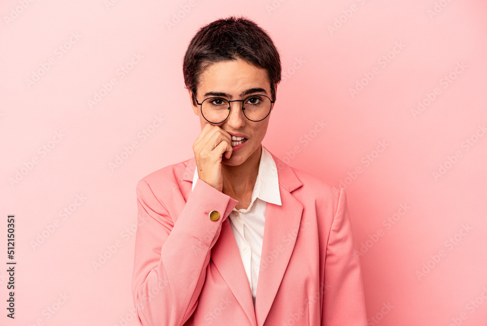 Young business woman wearing a pink blazer isolated on pink background biting fingernails, nervous and very anxious. Young business woman wearing a pink blazer isolated on pink background biting fingernails, nervous and very anxious.
