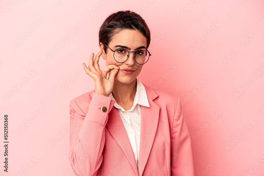 Young business woman wearing a pink blazer isolated on pink background with fingers on lips keeping a secret. Young business woman wearing a pink blazer isolated on pink background with fingers on lips keeping a secret.