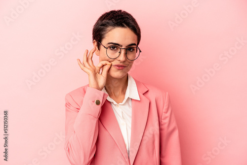Young business woman wearing a pink blazer isolated on pink background with fingers on lips keeping a secret.