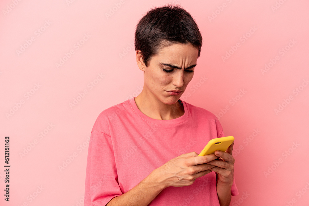 Young caucasian woman holding mobile phone isolated on pink background Young caucasian woman holding mobile phone isolated on pink background