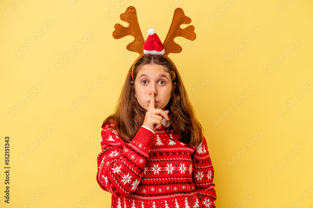 Little caucasian girl wearing a Christmas reindeer hat isolated on yellow background keeping a secret or asking for silence. Little caucasian girl wearing a Christmas reindeer hat isolated on yellow background keeping a secret or asking for silence.