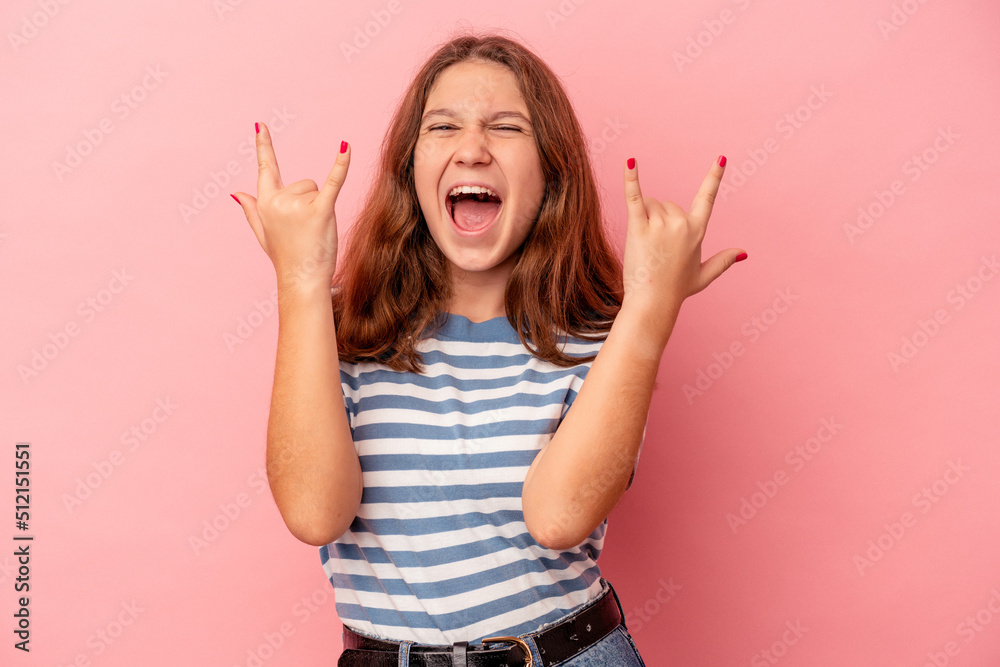 Little caucasian girl isolated on pink background showing a horns gesture as a revolution concept. Little caucasian girl isolated on pink background showing a horns gesture as a revolution concept.