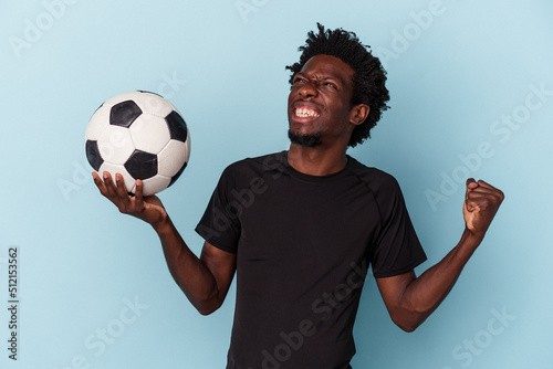 Young african american man playing football isolated on blue background